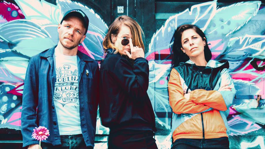 Shirley Holmes Die Band Shirley Holmes steht vor einer Graffiti-Wand